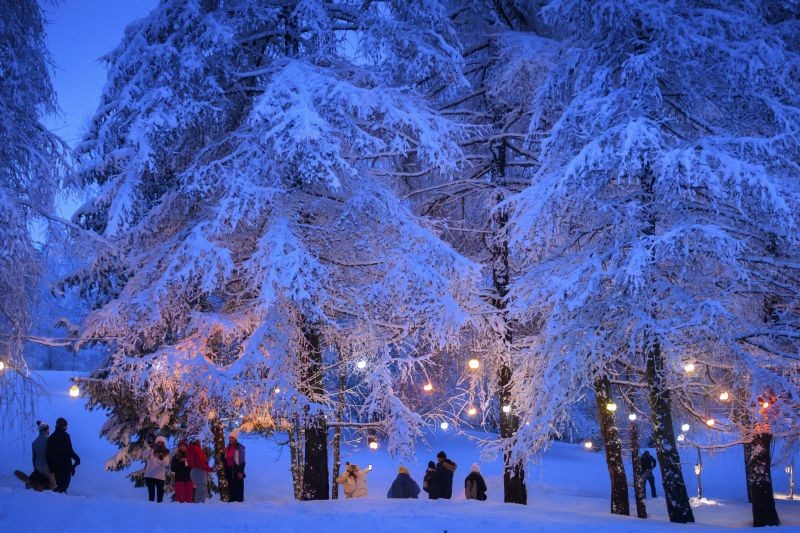 Crans Montana: People wearing protective face mask walk under snowfall the 2 km long snow-covered Lantern Path (chemin des lanternes) between Lake Moubra and Lake Etang Long during the coronavirus disease (COVID-19) outbreak, in the Alpine resort of Crans-Montana, Switzerland, Saturday, Jan. 30, 2021. AP/PTI